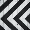 Black and white geometric pattern on wooden planks, ideal for modern design backgrounds.